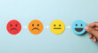 © Mujhid_Muneer - Customer satisfaction feedback concept shown by hand placing a happy smiley face on blue background