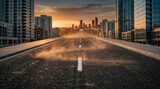 Empty urban highway leading through modern downtown skyscrapers at dramatic sunset light