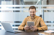 © Liubomir - Digital transformation and remote work, professional man using a tablet for business communication in a modern office. Corporate employee analyzing data and managing workflow with mobile technology.