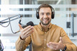 © Liubomir - Podcast host recording audio content, man speaking into microphone with headphones in modern office studio. Professional broadcaster sharing information and communicating with audience during digital.