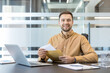 © Liubomir - Professional business communication and document management, smiling man holding envelope and letter at office desk with laptop. Efficient administrative workflow and corporate correspondence.