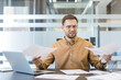 © Liubomir - Workplace stress and burnout, frustrated businessman holding paperwork at office desk with laptop. Professional employee reviewing documents and analyzing data under pressure, managing heavy workload.