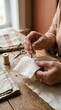 © NalLena - Person hand sewing a linen fabric with a needle and thread at a wooden table, handmade craft