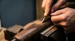 © ABD - Macro view of craftsman's hands carefully carving a detailed diamond pattern into a wooden gunstock in a shop.