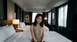 © HariBudi - Young Asian woman sitting happily on a hotel bed indoors