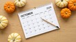 © Umnat - October 2026 calendar month on a wooden background with pumpkin decorations.