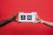© ADDICTIVE STOCK - Diverse hands hold retro flip clock at seven o'clock