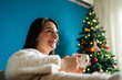 © ADDICTIVE STOCK - Woman enjoy Christmas at home with festive mug and tree
