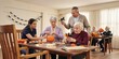 © CREATIVE STOCK - Group of seniors and caregiver crafting halloween decorations in a community center, halloween theme, halloween celebration