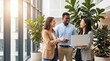 © AspctStyle - Diverse professional team smiling and looking at laptop in bright modern office atrium, capturing workplace happiness and collaboration for human resources marketing and corporate recruitment.