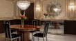 © Djemari - Luxurious dining room with a polished wooden table, crystal chandelier, and ornate sunburst mirror.