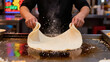 © Rachakrit - Handmade pizza dough tossing with flour on hot cooking surface