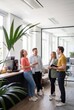 © Rendara Studio - Coworkers laughing together at the office coffee counter