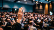 © Emran - hand raised in audience at large conference hall or seminar event showing participation and asking question during presentation discussion.