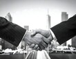 © saku - Two businessmen shaking hands in front of a modern city skyline, signifying a successful agreement and partnership.