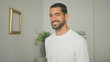 © Krakenimages.com - Man smiling with visible face and beard in a studio apartment interior wearing a white tshirt; friendly confidence.