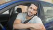 © Krakenimages.com - Man leaning out of blue car window with forearm on door, wearing seatbelt and smiling toward camera on street; friendly confidence.