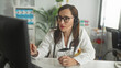 © Krakenimages.com - Woman doctor with stethoscope gesturing and pointing at computer screen during telemedicine consultation in a medical building; compassionate remote care.