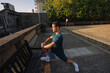 © Angel Santana/Stocksy - Young man stretching leg before morning run