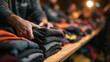 © BlackBridge Media - Volunteer Hands Organizing Warm Clothes for Charity Donation