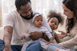 © ultramansk - A cheerful interracial family laughs together during floor playtime in a bright modern living room, full of family fun and play ideal for parenting and wellbeing content.