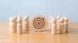 © Graphic Plenty - Strategic focus and collaborative teamwork wooden figures surrounding a target representing shared goals and unified effort in a business environment