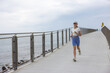 © leungchopan - Fit woman jogging along bridge metal railing