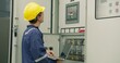 © HarryKiiM Stock - An electrical engineer performs a system diagnostic check with a laptop, conducting maintenance on an industrial power distribution control panel in a factory.