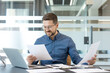 © Liubomir - Corporate productivity and business analysis, professional man reviewing financial documents and reports at office desk with laptop