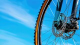 Close-Up of Mountain Bike Wheel with Disc Brakes Against Clear Blue Sky Background