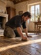 © Serjio - Hombre restaura un piso de madera en una casa antigua con luz natural