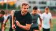 © mirukser - A focused male athlete leads a group of runners on a track, training for speed and endurance.