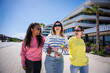 © CarlosBarquero - Female friends enjoy a cheerful walk together on a sunny day in a clean residential promenade with palm trees and contemporary buildings.