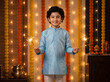 © Someone Cooked Here - cheerful young indian boy in blue traditional kurta holding two glowing diwali sparklers looking at camera for festive holiday marketing ad