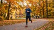 © mdnazirhossain - Fit young man running on a path in a park with colorful autumn trees and fallen leaves in the fall season during a sunny day