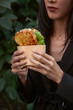 © Danil Nevsky/Stocksy - Woman holding sandwich in paper wrapper during business lunch