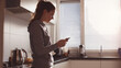 © syaifuddin - authentic lifestyle photography of a young professional woman preparing for the workday in a realistic apartment, checking her schedule on a smartphone while preparing coffee in the kitchen
