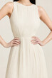 © Hazel - sleeveless beige pleated dress with hands on waist
