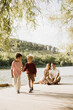 © BGStock72 - Children enjoy a playful moment by the peaceful lakeside while family relaxes