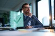 © Elena - Thoughtful businessman seated at a contemporary desk in a brightly lit office with large windows, his gaze fixed on a translucent holographic green checkmark floating before him