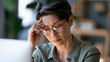 © Nataliya - Asian mature woman wearing glasses and looking away from a bright computer display, rubbing tired eyes, eye strain, headache, digital health, home office, natural skin texture,