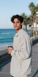 © Andrii Zastrozhnov - Young man standing on seaside promenade holding coffee cup with palm trees and ocean view for lifestyle portrait and travel banner design
