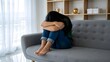 © ChauMinh - Sad woman sitting on sofa with head buried in knees at home