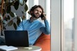 © Prostock-studio - Smiling Caucasian Male Working On Laptop While Engaged In Phone Conversation At Vibrant Modern Office Space, Showcasing Professionalism And Focus In A Productive Business Setting.
