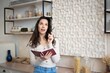 © Prostock-studio - Focused Young Woman Of Caucasian Descent Writing In Notebook With Pen While Sitting In Modern Kitchen, Engaging In Creative Process And Planning, Inspired By Ideas And Thoughts.