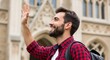 © Dwi - Happy bearded male student waving hello while visiting a historic university campus during a sunny autumn afternoon stroll in the city