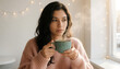 © Amrizal - Young thoughtful woman enjoying a hot drink from a ceramic cup near a window in a cozy atmosphere, generative AI