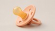 © Svetlana - Peach silicone baby pacifier with rounded nipple on a neutral beige background, isolated infant comfort and feeding accessory