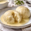 © mifhart - Traditional Germknödel yeast dumplings with vanilla sauce, fluffy steamed sweet buns on a plate, classic Austrian and Bavarian dessert