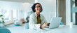 © Júlia Amaral - Woman laughs while working on laptop in office.